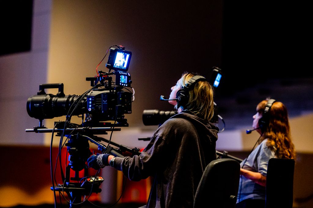 A film crew intensely operating high-end camera equipment during an indoor shoot.