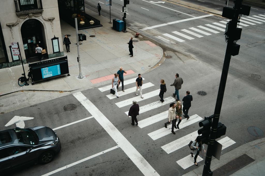 Aerial view of people crossing a city street at a pedestrian crosswalk.